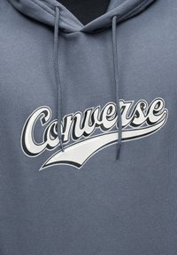 Γκρι φούτερ με κουκούλα και μπροστινά κορδόνια, με λευκό και μαύρο στυλιζαρισμένο λογότυπο "Converse" στο στήθος.