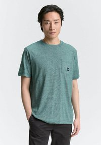 Groen gestreept T-shirt met ronde hals, korte mouwen en een borstzak met een klein logo op de patch. Glad textuur.