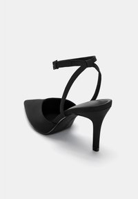 Black high-heeled shoe with a pointed toe, soft fabric upper, and an ankle strap secured with a buckle. Sleek and minimal design.