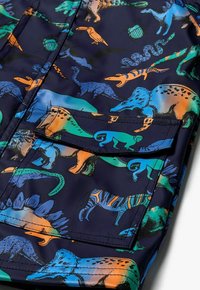 Kolorowa tkanina z różnorodnymi ilustracjami zwierząt, w tym dinozaurów i gadów, na ciemnogranatowym tle.