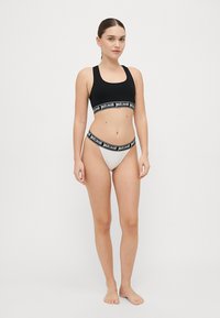 Haut court noir avec bande de marque et bas de bikini gris clair avec taille assortie. Tissu doux, design ajusté. Style minimaliste.