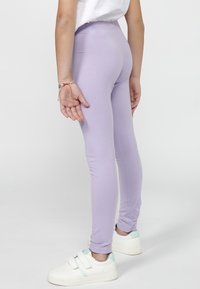 Leggings lilas en matériau doux avec une coupe ajustée. Associez-les à des baskets blanches avec un accent vert menthe.
