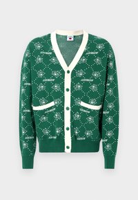 Cardigã verde com decote em V, com trim creme, apresentando um padrão de gelados por todo o lado, duas bolsas frontais e fecho com botões.