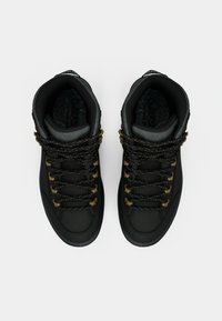 Zwarte hoge sneakers van textiel met een gestructureerde stof, gouden oogjes en gepatterde veters. Voorzien van een gevoerde kraag en een grijze binnenvoering.