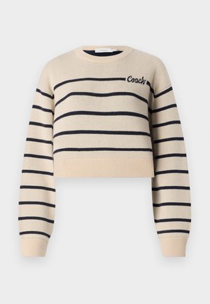 Beige lyhytneule, jossa on tummansinisiä vaakaraitoja, pyöreä kaula-aukko ja resorit. "Coach" brodeerattu samanvärisellä tummansinisellä langalla. Pehmeä rakenne.