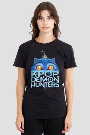 Young person wearing black t-shirt with large graphic of blue cat eyes and a bird above text "K-POP DEMON HUNTERS" on front.