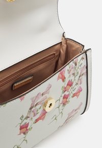 Torebka w kwiatowy wzór wykonana z białej teksturowanej skóry ekologicznej, z złotym zapięciem na zatrzask i brązowym satynowym wnętrzem z kieszenią na zamek.