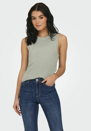 Débardeur côtelé gris clair avec un col montant et une coupe sans manches, associé à un jean taille haute en denim bleu foncé.