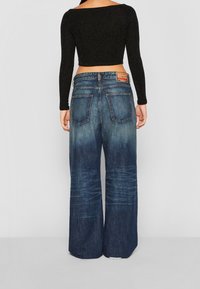 Kangasshortsit leveällä lahkeella ja haalistuneella sinisellä pesulla, joissa on korkea vyötärö, viisi taskua ja nahkabrändipatch takana.