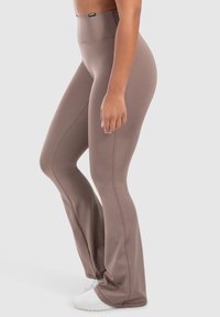 Bruine uitlopende leggings van rekbare stof met een gladde textuur, voorzien van een hoge tailleband en zijnaaddetails.