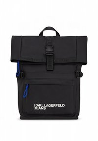 Juoda kuprinė su užlenkiamu viršumi, pagaminta iš tekstūruotos medžiagos, su priekyje esančia užtrauktuko kišenėle, mėlynu akcentu ir baltos spalvos logotipo detalėmis. Įtraukti reguliuojami dirželiai.