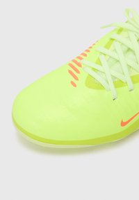 Sapatilha atlética amarelo-neon com uma textura suave, detalhes em laranja contrastantes e atacadores verde-claro. Apresenta um design aerodinâmico.