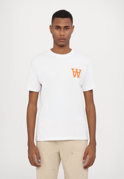 Hvid bomulds-T-shirt med et lille orange "W" logo på venstre bryst. Korte ærmer og rund halsudskæring. Glat tekstur.