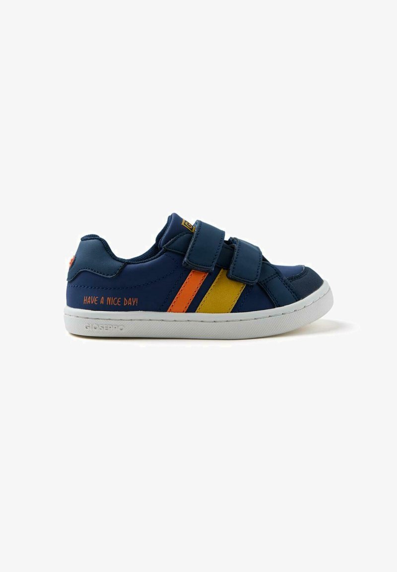 Zapatilla azul marino con dos tiras de velcro, con franjas naranjas y amarillas. El texto en el costado dice: "¡QUE TENGAS UN BUEN DÍA!" Suela de goma blanca.