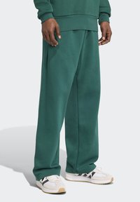 Gröna sweatpants i mjukt tyg med avslappnad passform, med elastisk midja och sidofickor. Matchas med vita och svarta sneakers.