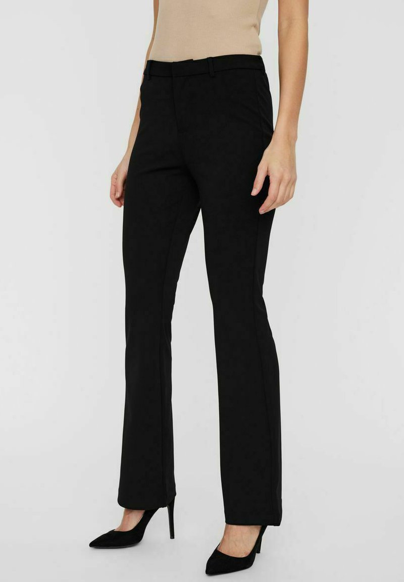 Pantalon noir ajusté avec une coupe slim, texture soignée, passants de ceinture et taille mi-haute. Assorti avec des escarpins noirs.