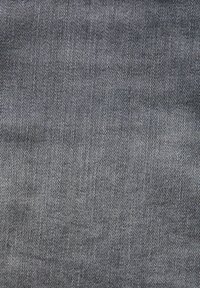 Gros plan sur un tissu en denim gris montrant la texture de la trame diagonale ainsi que des variations subtiles de teinte et d'épaisseur des fils.
