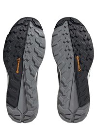 Schwarze und graue Gummisohlen von Schuhen mit einem robusten Profilmuster, strukturierten Oberflächen und einem orangefarbenen "Continental"-Logo an der Seite.