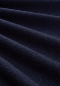 Dunkelblaues Gewebe mit glatter Textur, das subtile, gleichmäßig verteilte Falten aufweist, die ein sanftes Wellenmuster erzeugen.