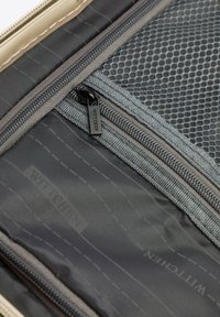 Šedý textilní interiér s síťovou kapsou a šedým zipem. Vyznačuje se hladkým povrchem a zesíleným šitím. Logo viditelné na textilu.