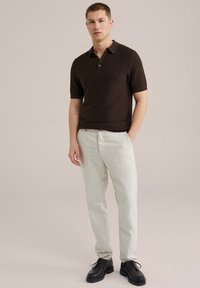 Rjav kratkosleevni polo majica, bež prugaste hlače, črne čevlje. Slim fit, lahka pletenina, gumb na ovratniku.