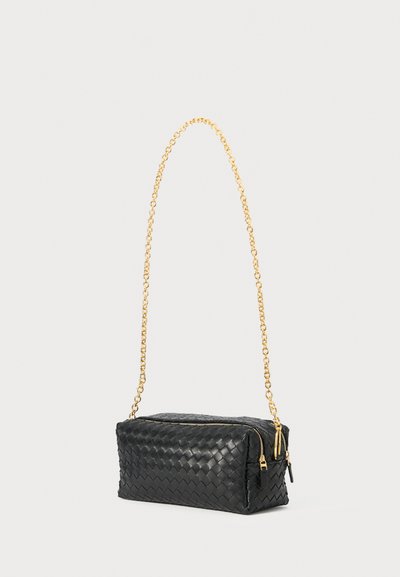 Borsa in pelle intrecciata nera con tracolla in catena dorata, forma rettangolare, chiusura con zip e due cursori per la zip. Dettaglio della superficie testurizzata.