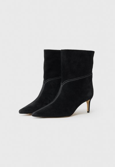 Schwarze Wildleder-Ankle Boots mit spitzem Zehenbereich und dünnem Absatz, die über eine weiße Naht entlang der Seitennaht verfügen. Glatte Textur und elegantes Design.
