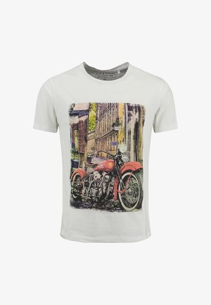 Męska biała koszulka z grafiką vintage czerwonego motocykla na tle miejskiej ulicy.