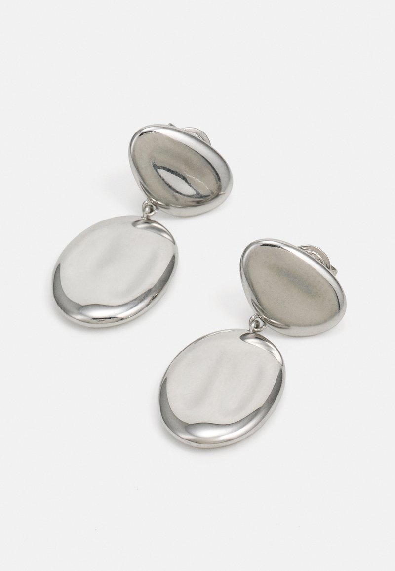 Pendientes de metal en tono plateado con un diseño ovalado liso y un acabado pulido. Dos colgantes ovalados interconectados cuelgan del tope de la tuerca.