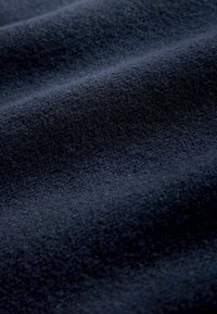 Marineblauer Stoff mit einer weichen, strukturierten Oberfläche, die sanfte Wellen und einen leichten Glanz aufweist, was auf ein Woll- oder synthetisches Mischmaterial hinweist.