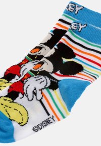 Colorful socks with blue cuffs and toes, featuring a cartoon character wearing red gloves and yellow shoes, with multicolored stripes in the background.