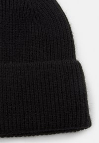 Crni pleteni zimski šešir s rebrastom teksturom i preklopom. Materijal izgleda mekano i blago pahuljasto, čime se povećava toplina.