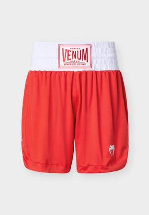 Shorts de boxe rouges avec une large ceinture élastique blanche arborant le logo "VENUM Pro Boxing" et un petit emblème blanc en forme de dent de serpent sur la jambe.