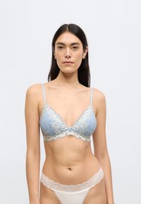 Ανοιχτό μπλε δαντελένιο σουτιέν με περίπλοκα κρεμ λουλουδάτα σχέδια· τρίγωνο σχήμα, ρυθμιζόμενες τιράντες και κυματιστή άκρη.