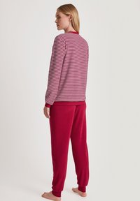 Streifenpullover in Pink und Rot mit gerippten Bündchen, kombiniert mit einfarbigen roten Hosen. Weicher Stoff, lässige Passform und elastischer Taillenbund.