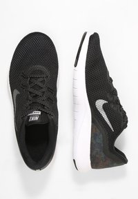 Černé sportovní boty z prodyšné síťoviny s texturovaným svrškem, bílými gumovými podrážkami a reflexními prvky. Rovné tkaničky a logo na jazyku.