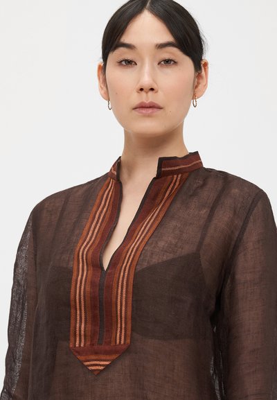 Hnedá ľanová tunika s výstrihom do V a zložitými oranžovo-červenými pruhovanými akcentmi na golieri. Ľahká a polopriesvitná textúra.