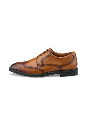 Mænds brune læder brogue wingtip sko med sort sål og snørelukning, vist i sideprofil mod hvid baggrund.