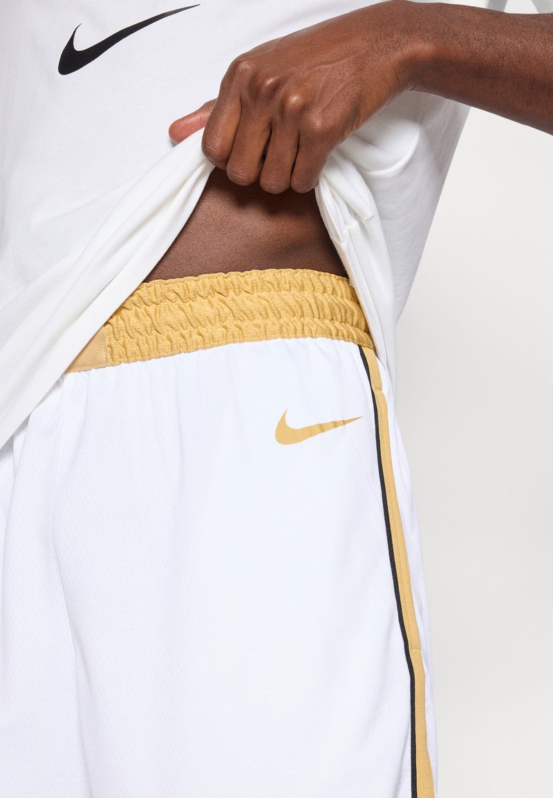 White athletic shorts with a yellow elastic waistband and black side stripe, featuring a small gold Nike logo on the front.