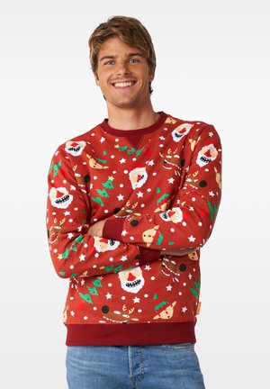 Roter Baumwollpullover mit einem Weihnachtsmuster, das Santa-Gesichter, Rentiere, Lebkuchenmänner und Weihnachtsbäume zeigt. Gerippter Ausschnitt und Bündchen.