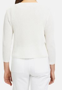Bílý pletený svetr s rib strukturou a tříčtvrtečními rukávy; má volný střih a texturovanou tkaninu. Zkrácená délka s horizontálně ribbeným vzorem.