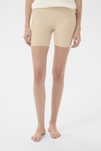 Bézs színű, elasztikus anyagból készült, testhezálló rövidnadrág, középhosszúságú, sima textúrával. Minimális dizájn, látható logók nélkül.