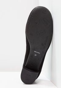Ballerine noire avec dessus en daim et semelle extérieure en caoutchouc noir texturé arborant des motifs embossés et un logo. Taille marquée 37, fabriquée en Espagne.