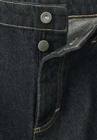 Jeans in denim nero con accessori in argento, dotati di chiusura a bottone, cuciture dorate a contrasto e una finitura in tessuto testurizzato.