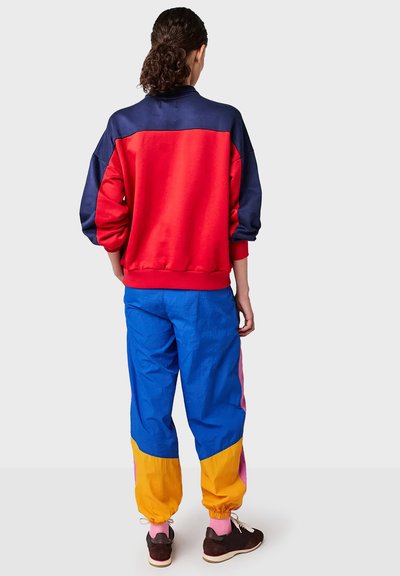 Red and navy sweatshirt with a relaxed fit; blue, pink, and yellow pants with elastic cuffs and a color-blocked design.