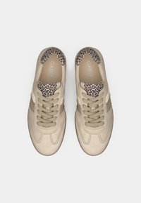 Μπεζ αθλητικά παπούτσια με λείο δερμάτινο επάνω μέρος, διακοσμητικά στοιχεία με υφή λεοπάρδαλης στη γλώσσα και ανοιχτό γκρι κορδόνια. Ελαστικές σόλες.