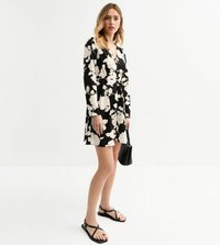 Robes longues à manches longues florales en noir et blanc avec un décolleté en V, jupe évasée et un sac à main noir. Accessoirisée avec des sandales noires avec une touche dorée.