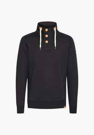 Schwarzer Pullover mit hohem Kragen, ausgestattet mit drei Holzknöpfen, cremefarbenen Kordeln und strukturiertem Rippstoff. Kleines Markenetikett am Saum.