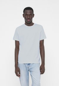 Light blue short-sleeve t-shirt made of cotton, featuring a crew neck and straight-cut design, paired with light denim jeans.