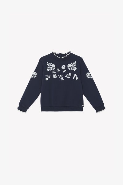 Tengerészkék pulóver fehér virágmintás hímzéssel, fodros nyakkal és mandzsettákkal, hosszú ujakkal és bordázott aljjal. Puha pamut anyag.